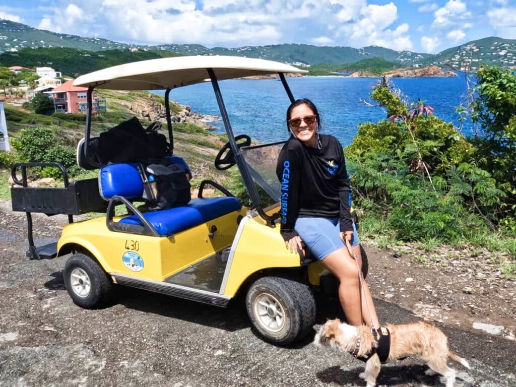 A woman with a dog sitting on a golf cart