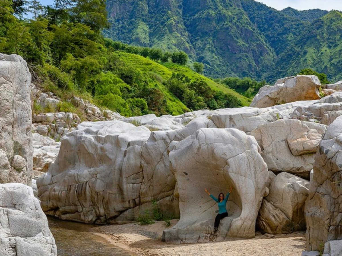 A woman posing for a photo at the white rocks between mountains in Cañón Blanco