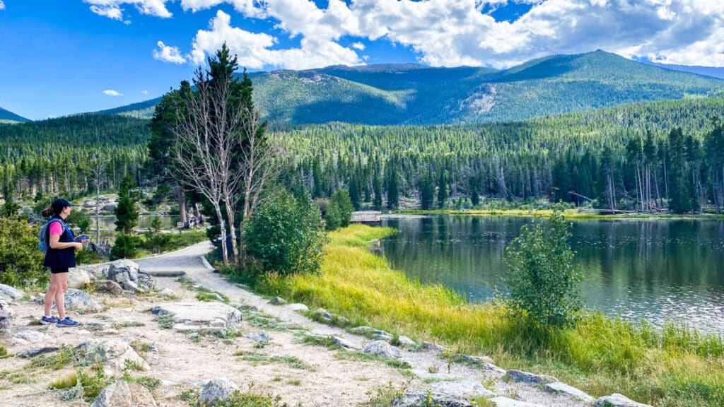 A woman overlooking the scenic view of Sprague Lake on a sunny day