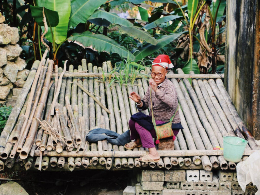 A woman sitting on bamboo bench wearing hat