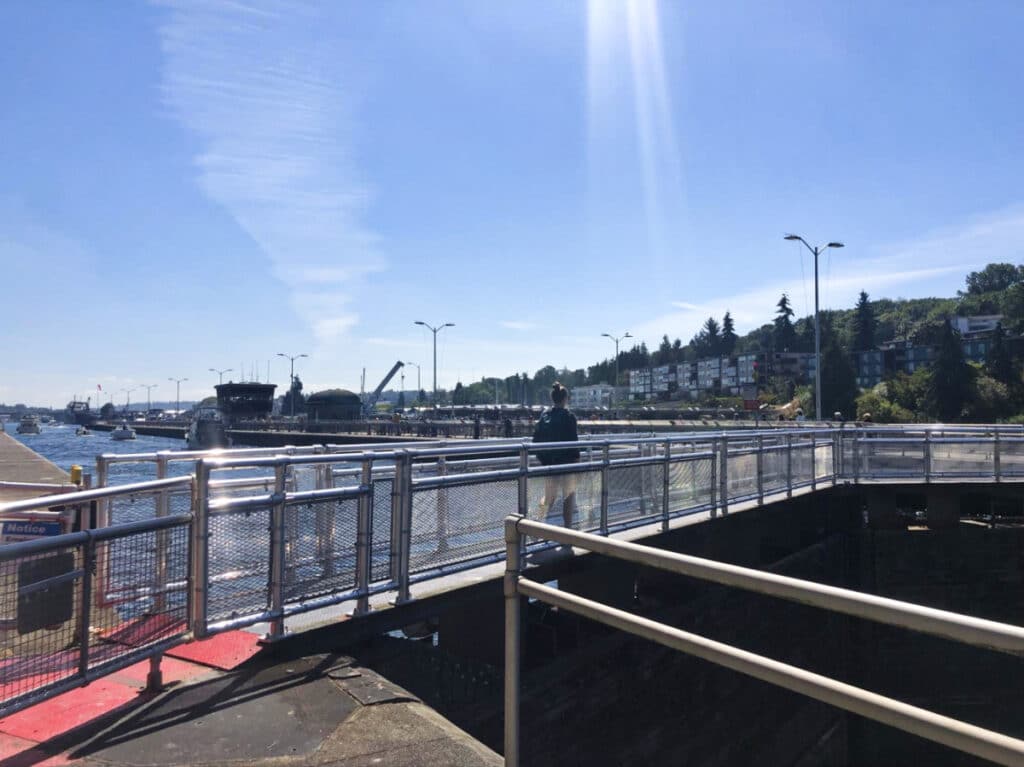 A woman walking along the Ballard Locks on a sunny Day
