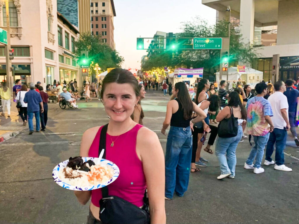 A woman posing for a photo while holding a plate of Jamaican jerk pork