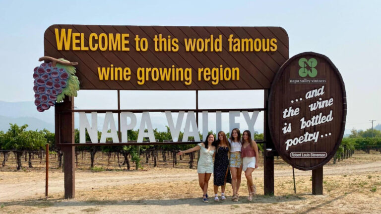A group of friends posing below the Welcome to Napa Valley signage