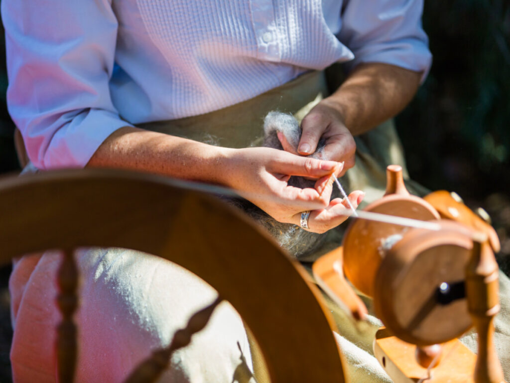 Wool spinning with vintage tools on old estate at Four Mile Historic Park