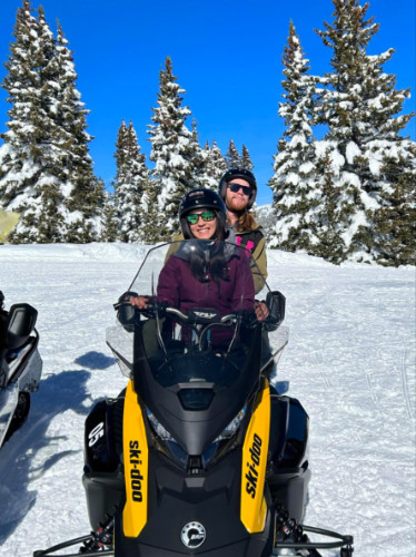 Writer Abigail and her husband riding the snowmobile