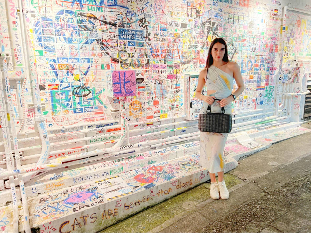 Writer Clara standing near a wall filled with colorful graffiti in Harajuku