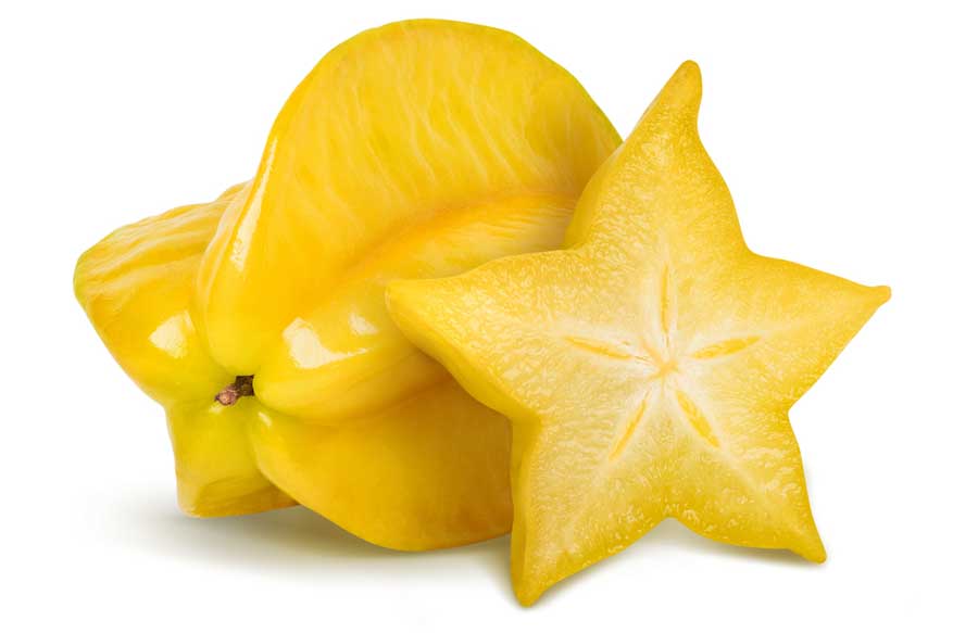 A whole and sliced yellow starfruit with a white background on it
