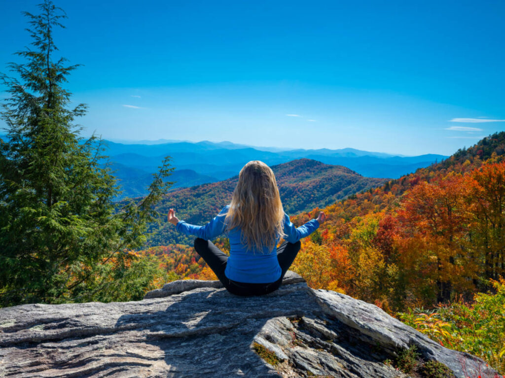 Woman practicing yoga and meditation in mountains during autumn hiking trip
