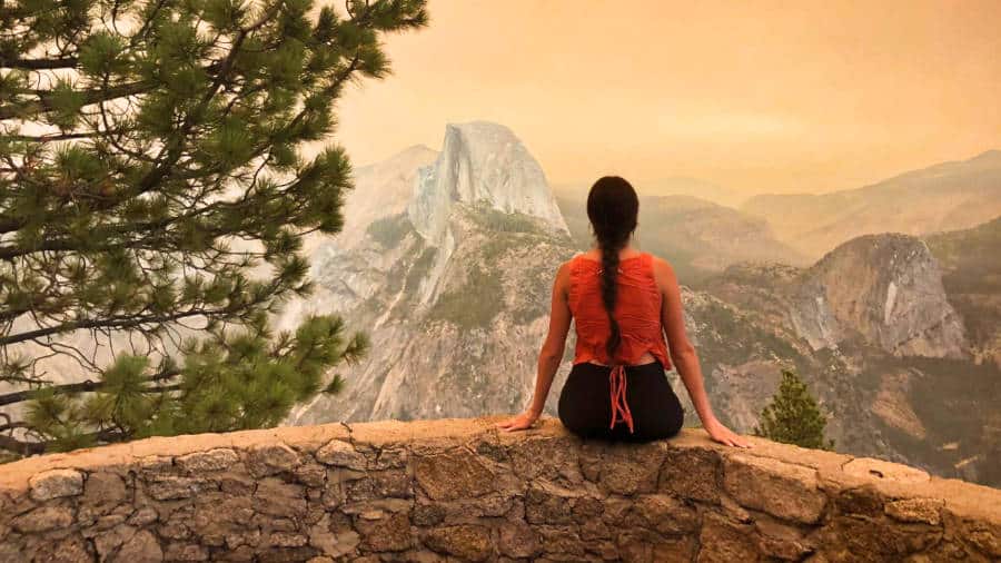 The author McKenna Mobley sitting at the viewpoint in Yosemite National Park during sunset