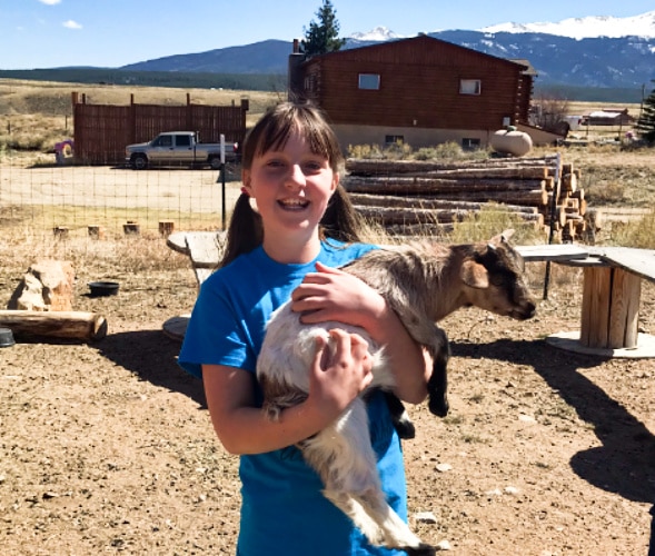 A young girl holding a small goat at Tenderfoot Farm