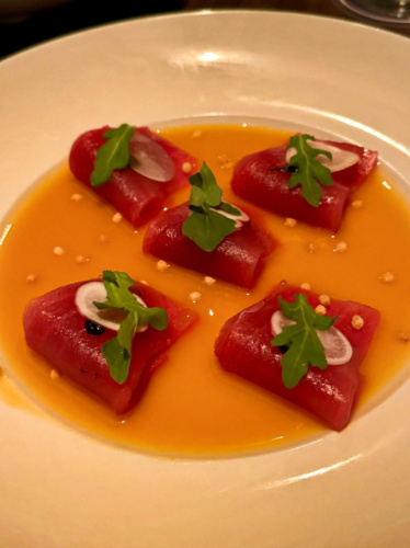 Closeup look of a plate with yuzu tuna slices on a sauce
