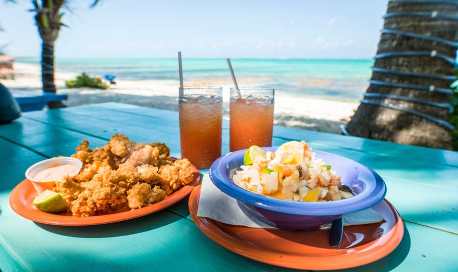 Salad on plate and drinks on glass with a view from the beach
