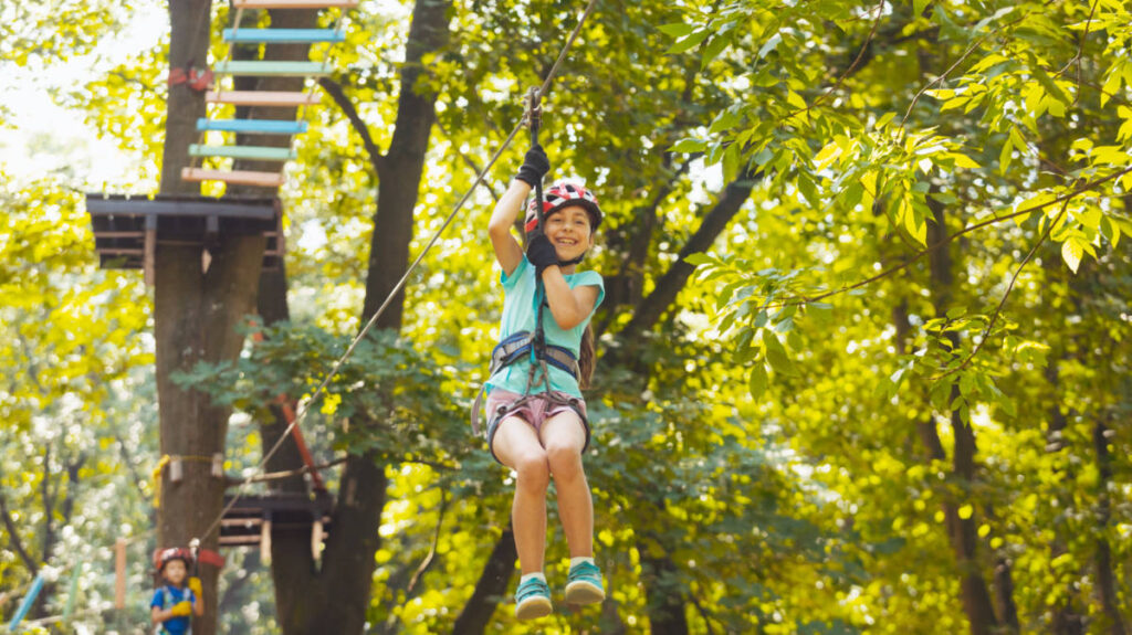 A little girl enjoying her ride on a zipline in ZipZone Outdoor Adventures