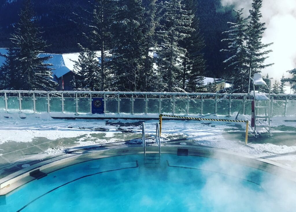 A winter scene of a ladder leading into hot springs in Banff National Park