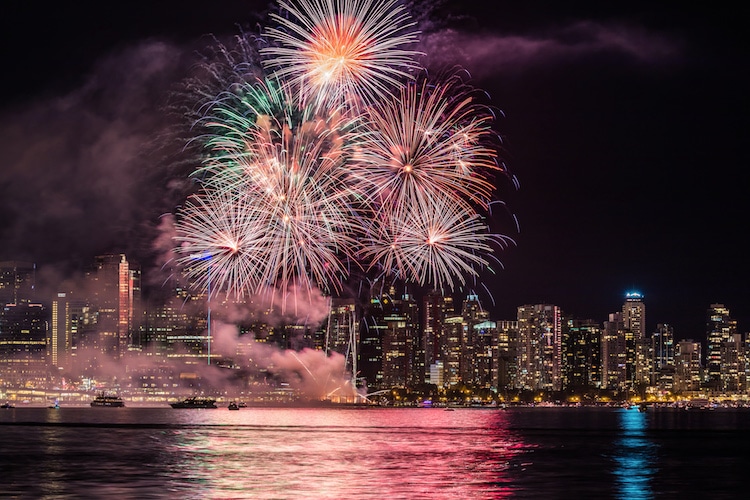 Fireworks light up the Vancouver Skyline above the water.