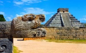 Ruins at Chichen Itza, Mexico - a stone animals head carving with a pyramid in the background