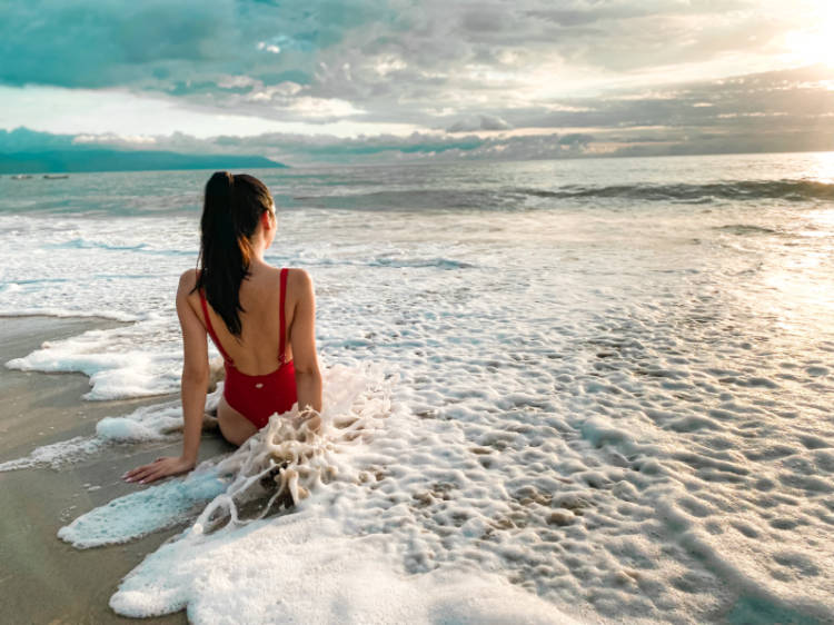 The author sitting on the sand above the sea on the Conchas Chinas Beach