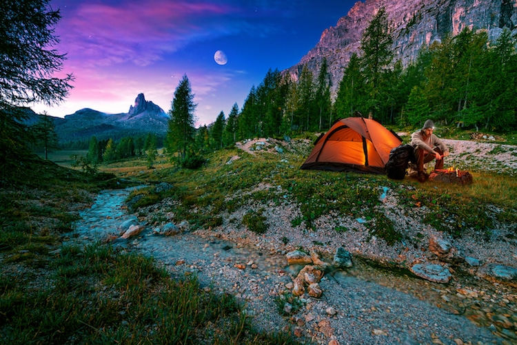 Colorful night sky and a man in a tent enjoying his camping