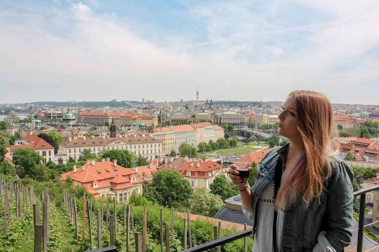 Travel Lemming Editor Taylor holding a glass of wine in front of Prague's Czechia's old town