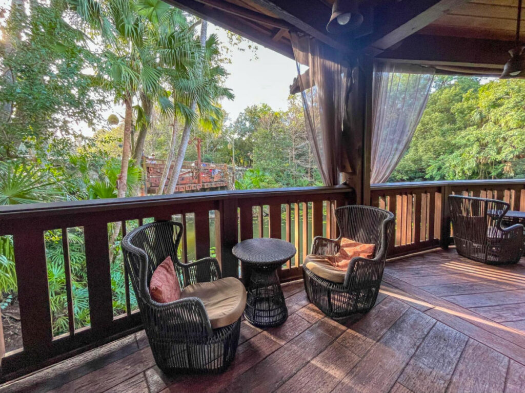 A cozy outdoor space with wooden deck, wicker chairs, and a table for relaxing at Nomad Lounge