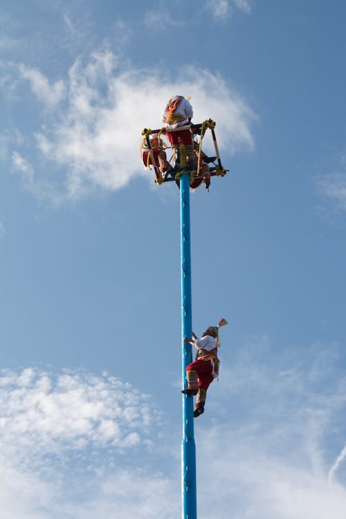 Mayan men do a rain dance up a tall poll