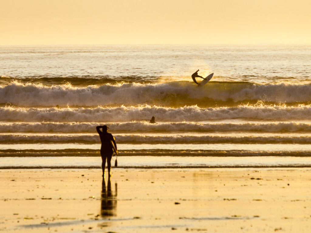 Surfers enjoying the beach in Tofino, holding a surfboard, ready to catch some waves and have fun in the water