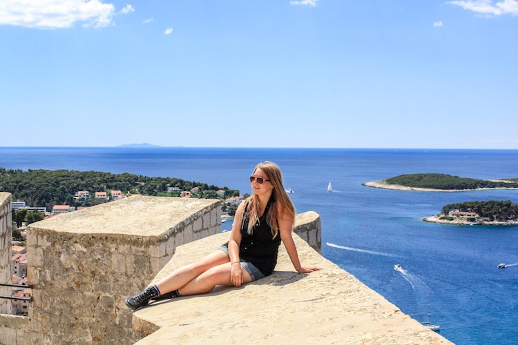 View of girl on top of fortress in Hvar with sea and islands on background