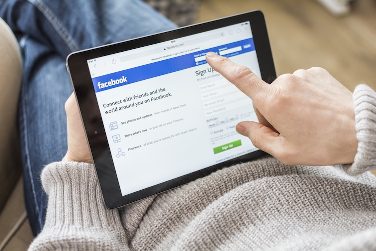 iPad on persons lap with facebook home page on screen