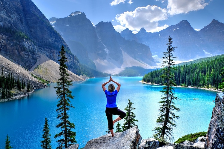 Woman practicing yoga by Moraine Lake Banff