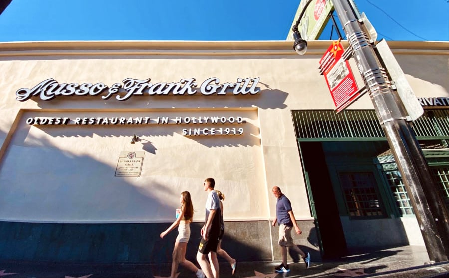 People walking pass outside ​​Musso & Frank Grill restaurant